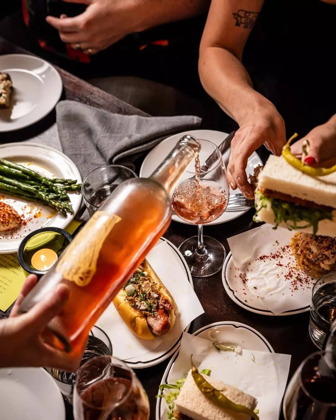 Wine being poured with share plates and hot dog at Love Tilly Devine Darlinghurst Sydney