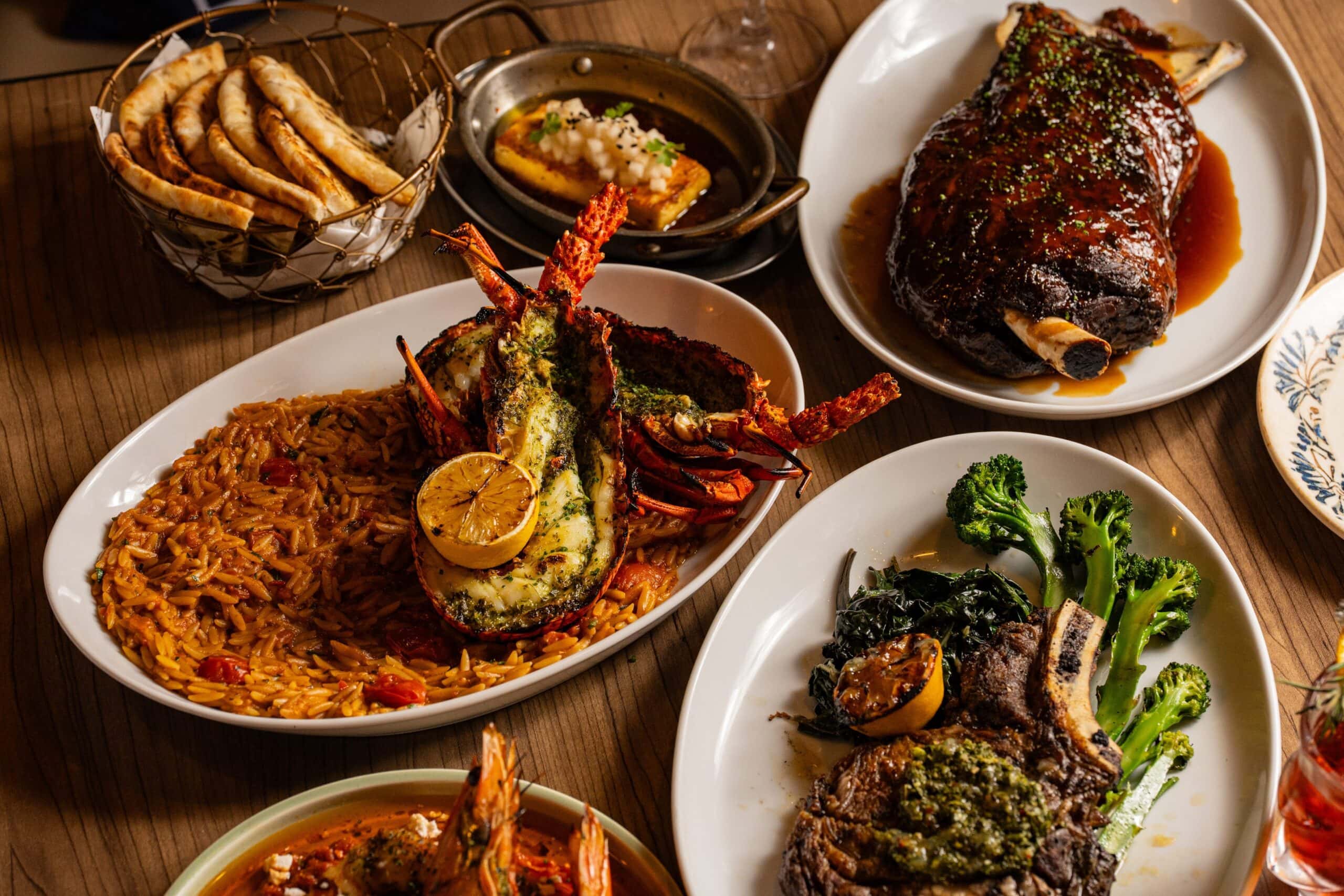 a spread of food on a table at jimmys kitchen in the rocks including steak, lobster with rice and char-grilled pita bread