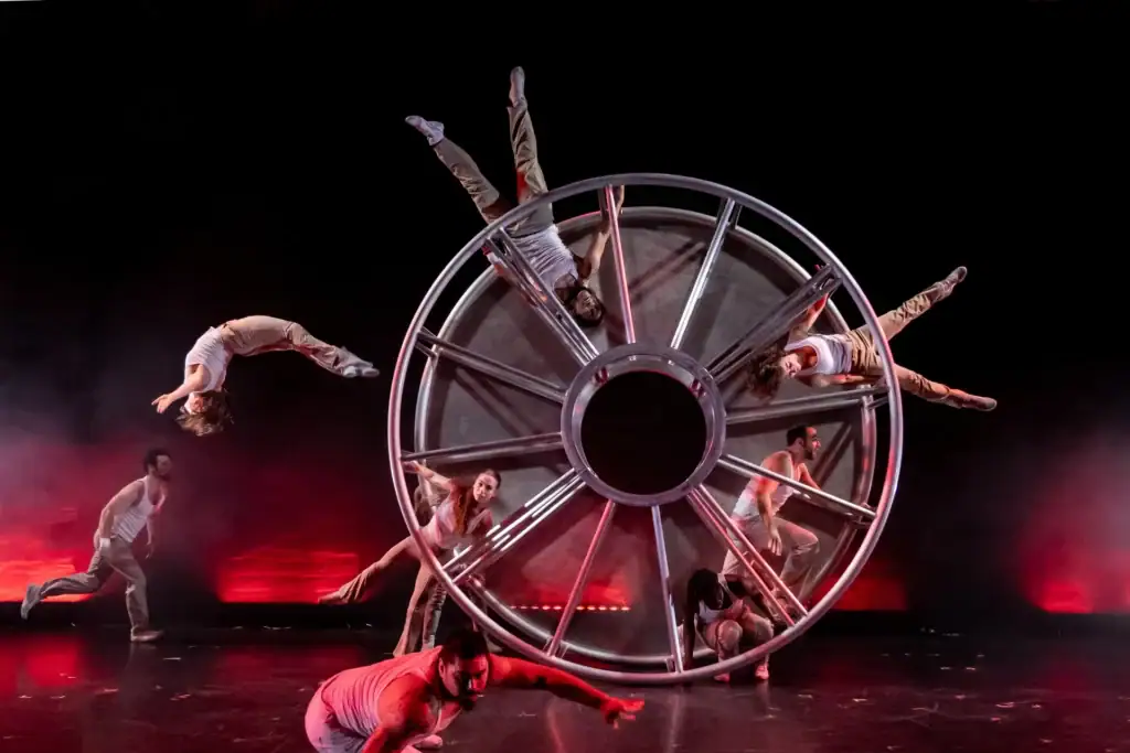 Performers interacting with a giant wheel as part of the ESCAPE performance.