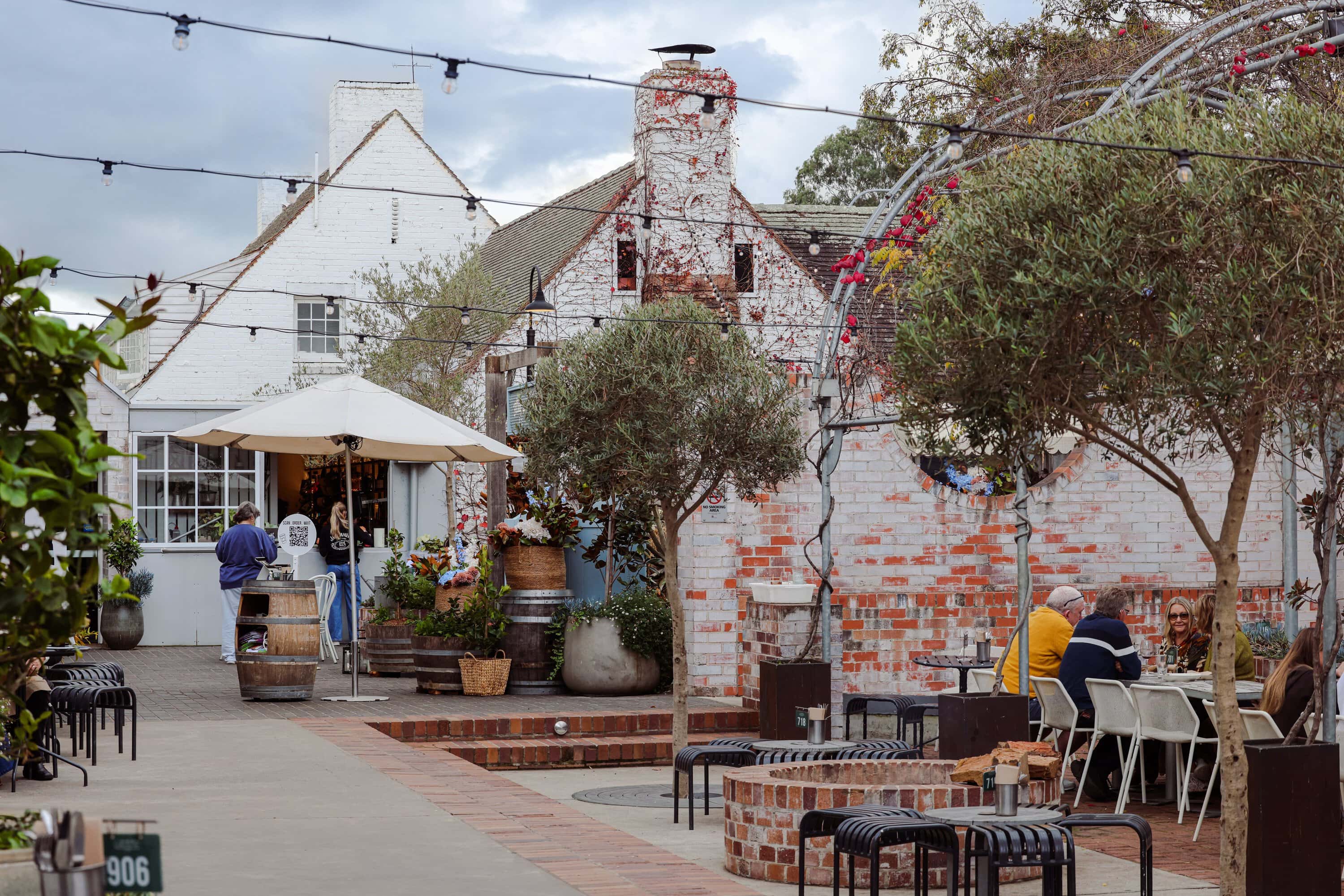 Diners seated in the courtyard beneath olive trees at Camden Valley Inn, Cawdor