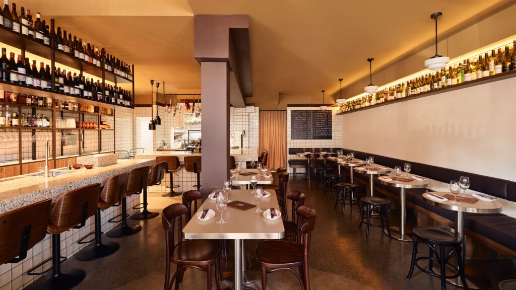 Dining room interior with floor-to-ceiling wine wall terrazzo bar and bentwood chairs at Caness Paddington Sydney