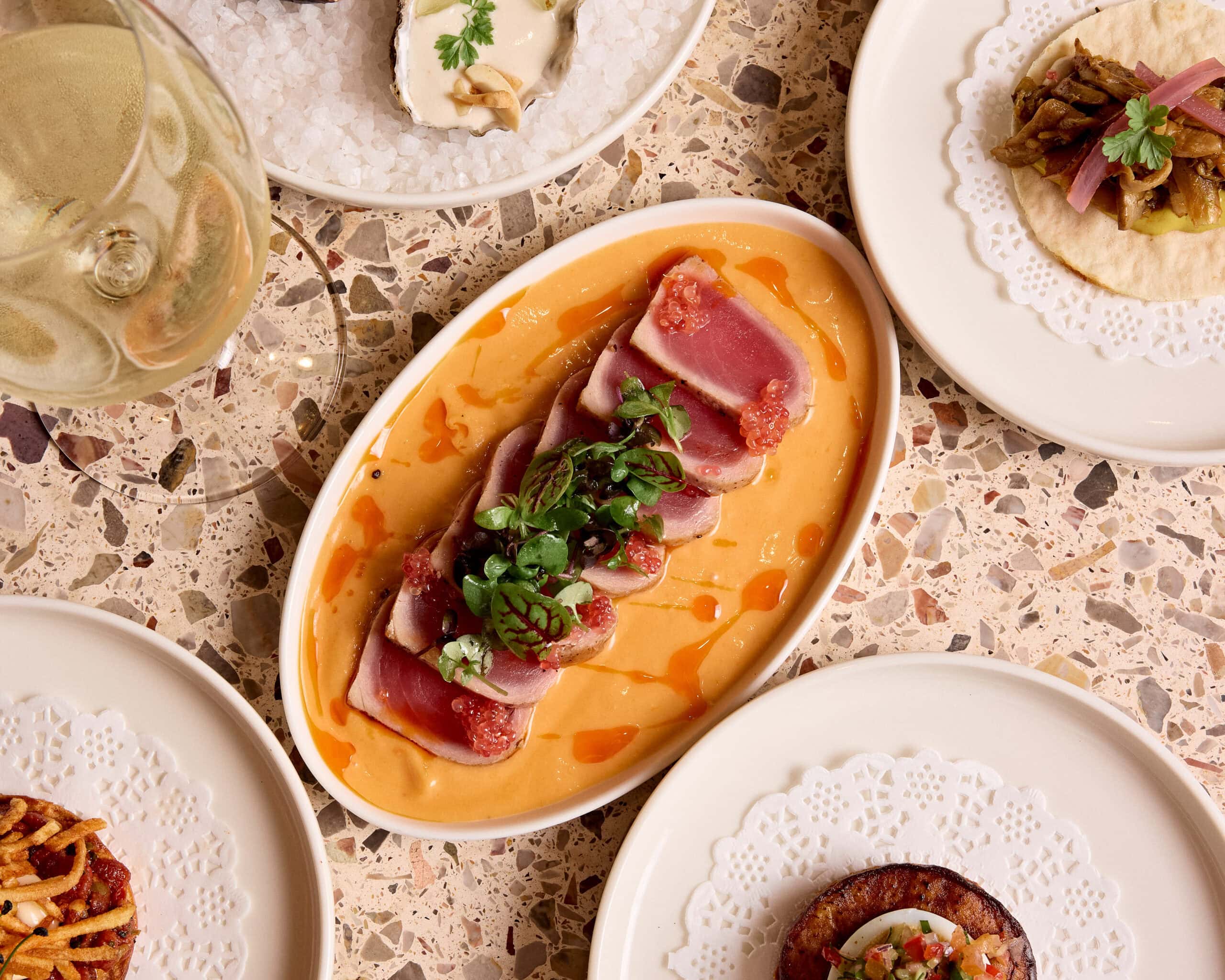 Seared tuna with romesco sauce and trout roe alongside oysters taco and share plates at Caness Paddington Sydney