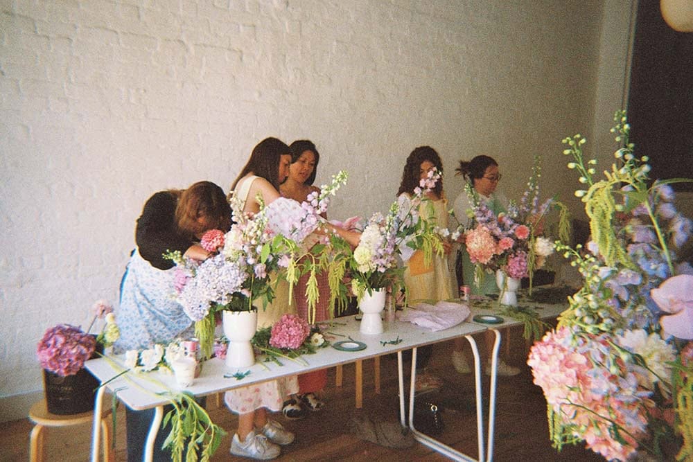 Participants creating large pastel floral arrangements during an Urban Antidote flower arranging workshop.