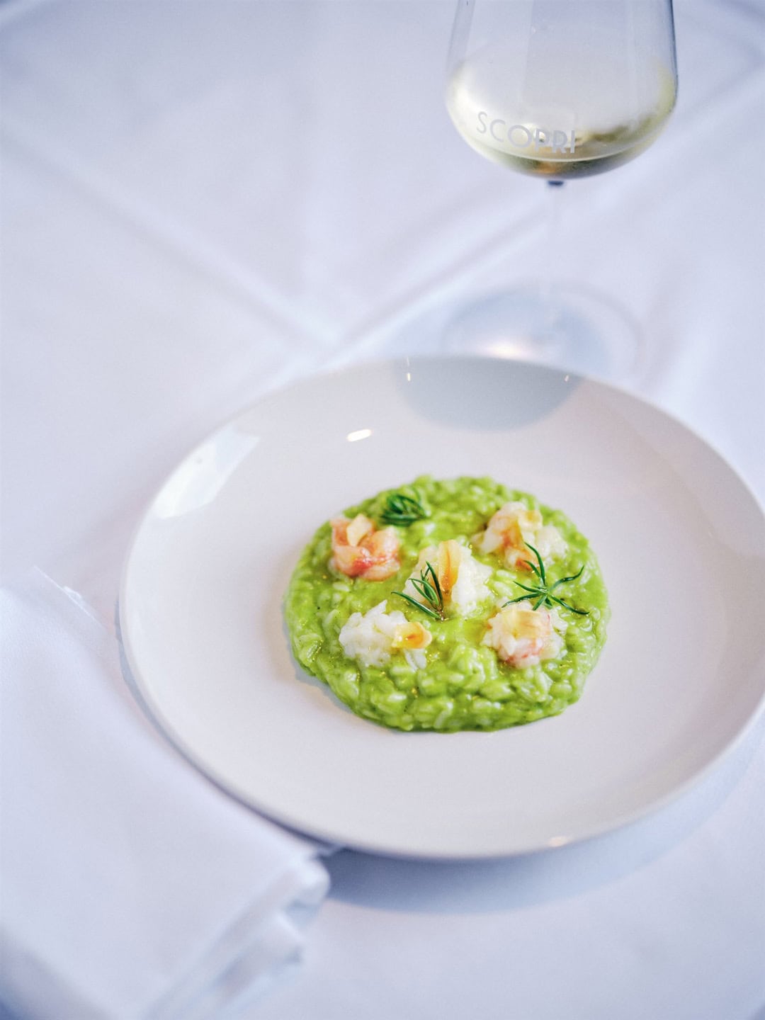 Famous risotto dish at Scopri Melbourne with white wine glass and white tablecloth