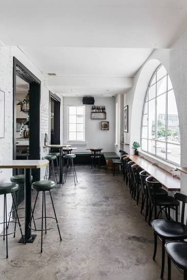 Bar Rochford interior with black bar stools concrete floors and large arched windows London Circuit Canberra