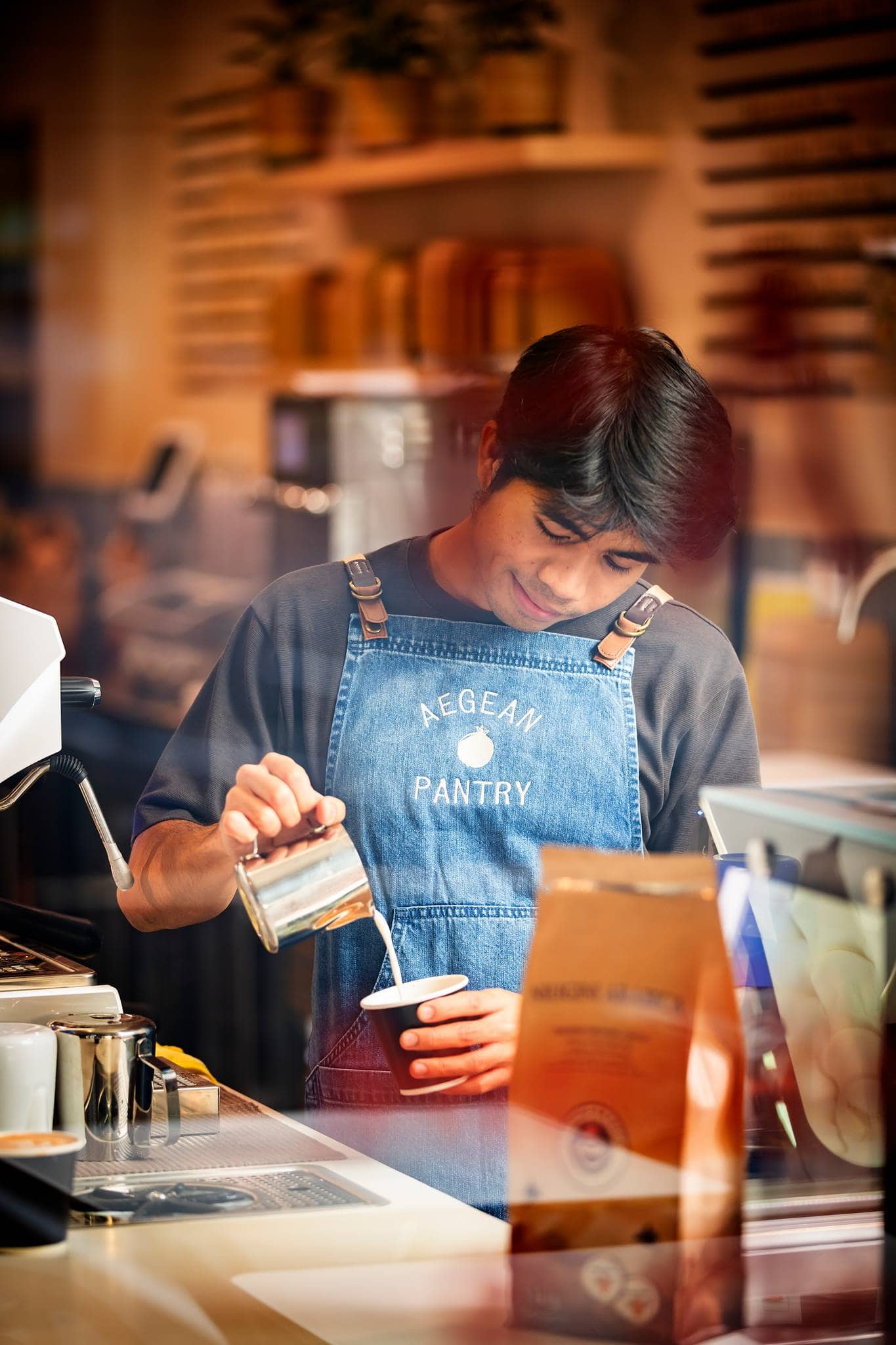 Barista pouring coffee in denim Aegean Pantry apron The Aegean Pantry Fyshwick Canberra