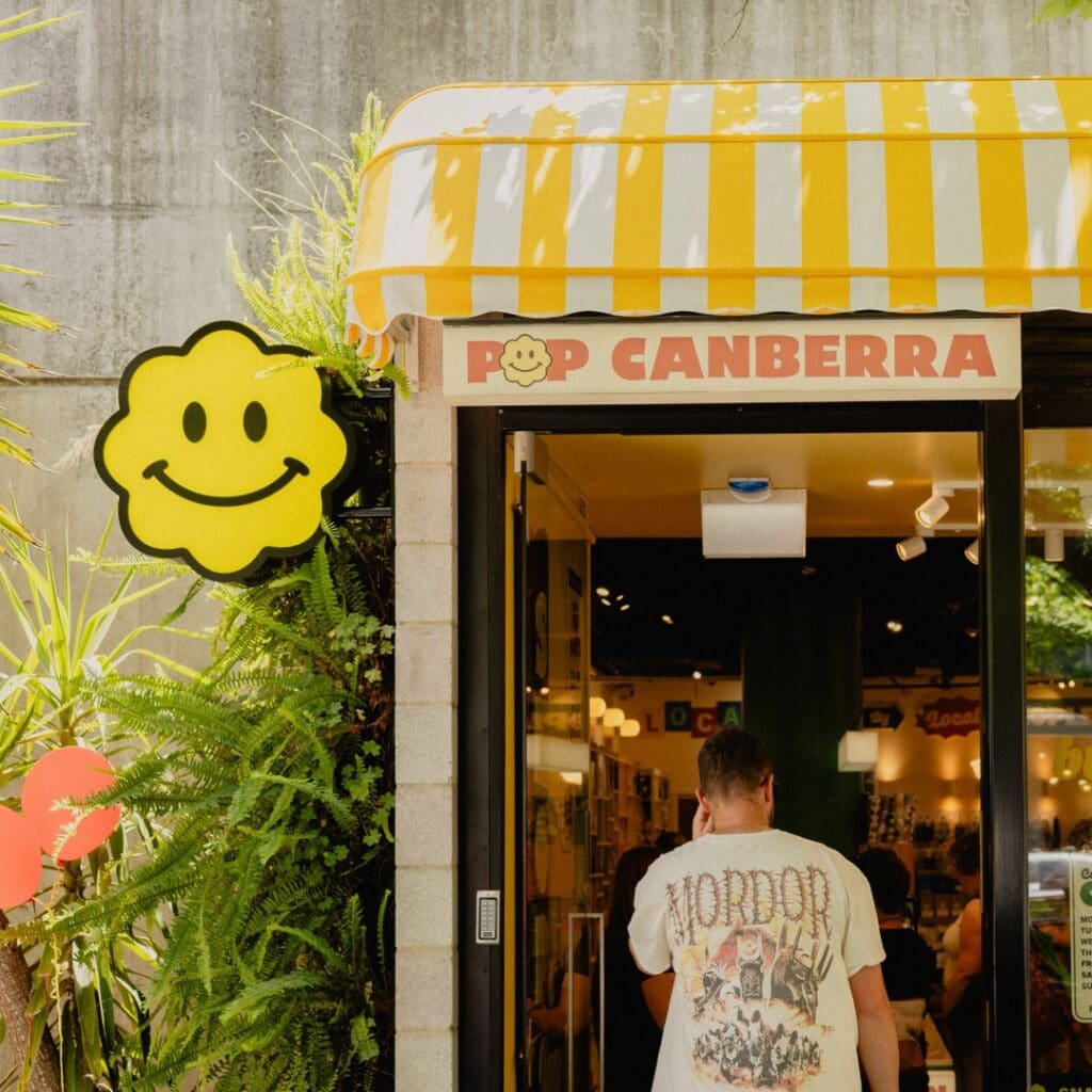 POP Canberra shopfront with yellow striped awning smiley face sign and customer entering Braddon Canberra