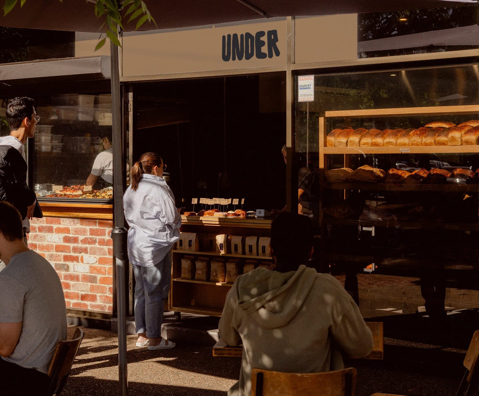 Under Bakery exterior shopfront with bread and pastry display shelves and customers queuing Mawson Canberra