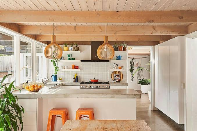 Bright open-plan kitchen at 100 Steps to the Beach in Anglesea, with timber ceilings, white cabinetry and orange stools.