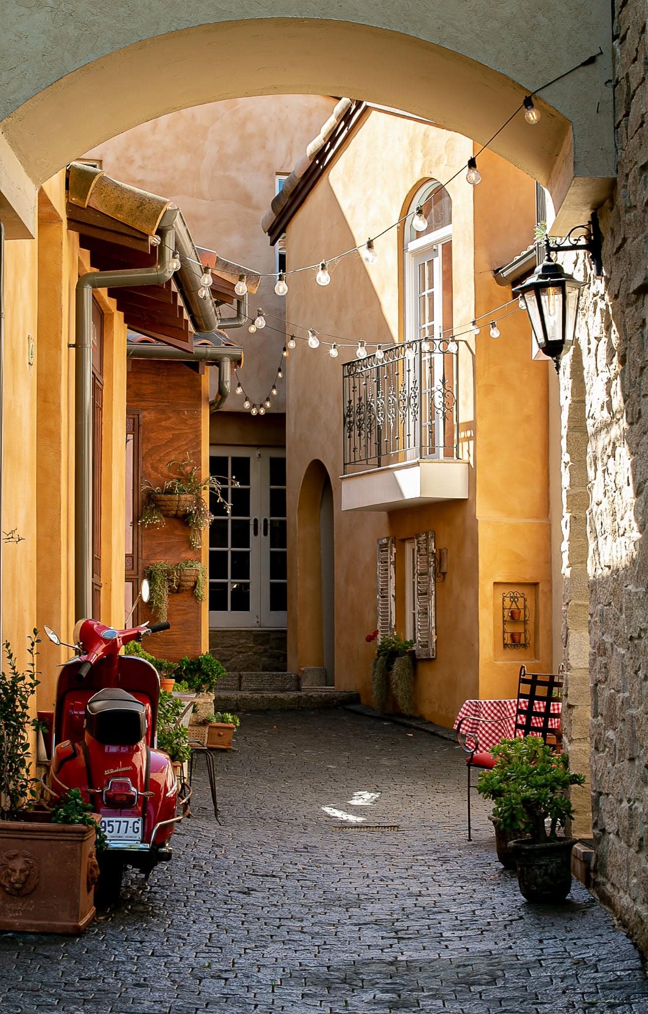 Archway entrance to Italian-style laneway with red Vespa Guestlands Arcadia Sydney