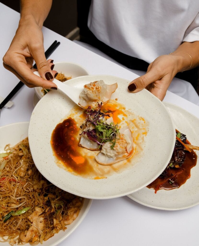 Someone being handed a plate of dumplings at Concubine in Adelaide,