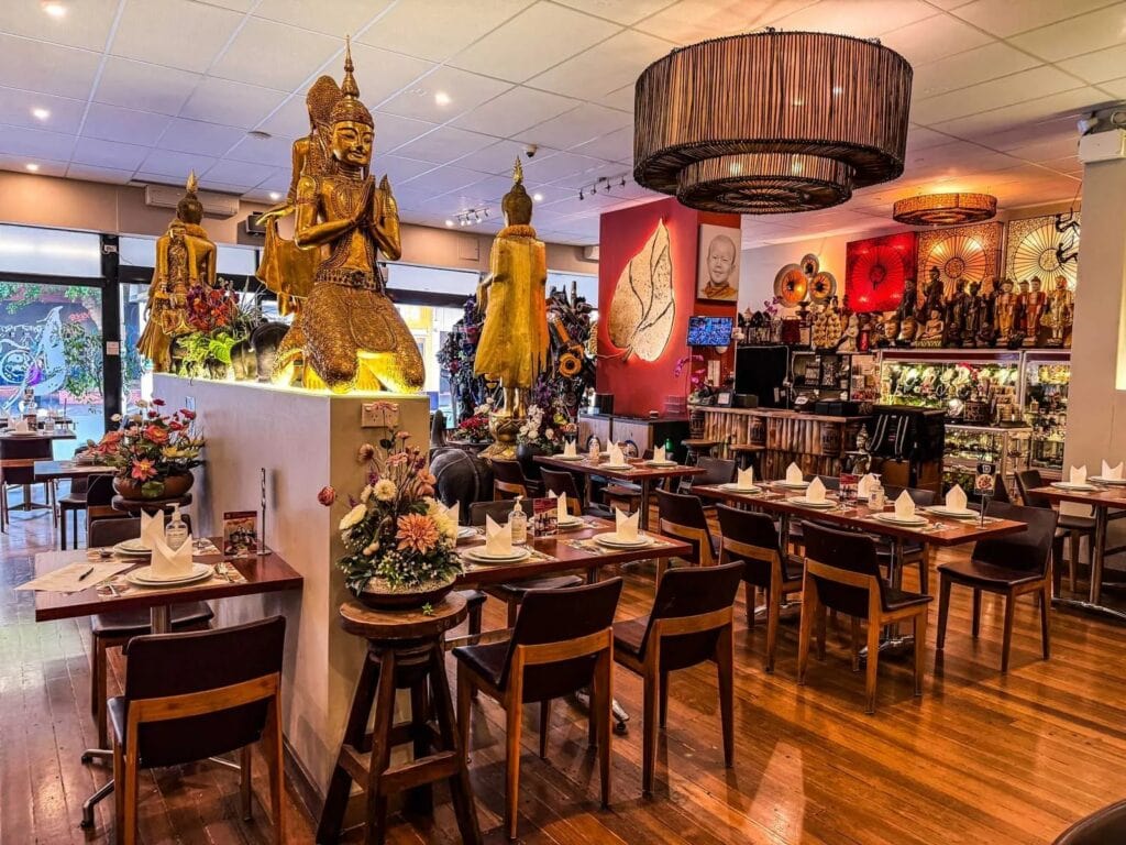 Dining room interior with gold Thai statues and timber floors at Thai Pothong Newtown Sydney