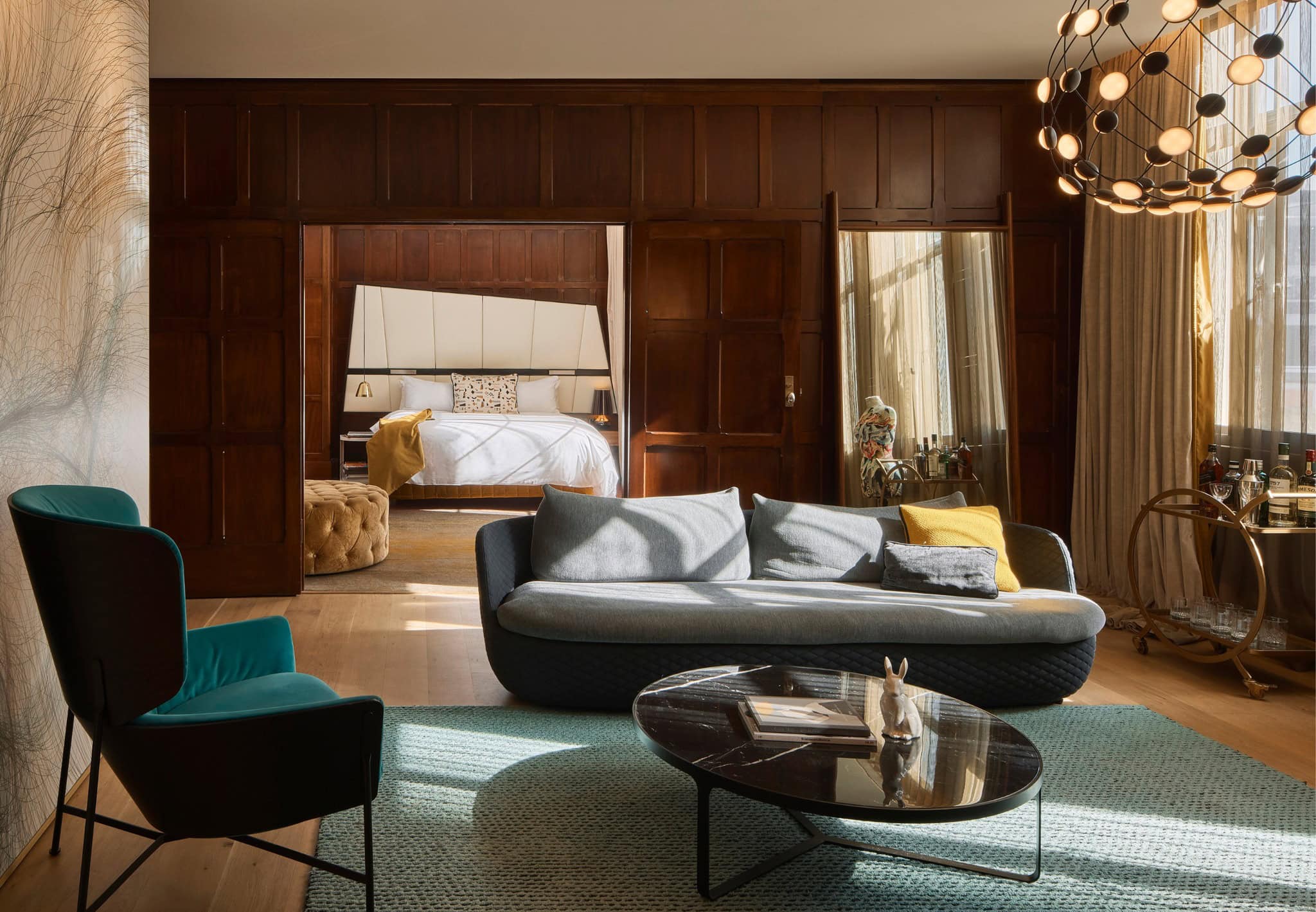 A suite at the QT Sydney with a loungeroom in the foreground and bedroom glimpsed through doors in the background