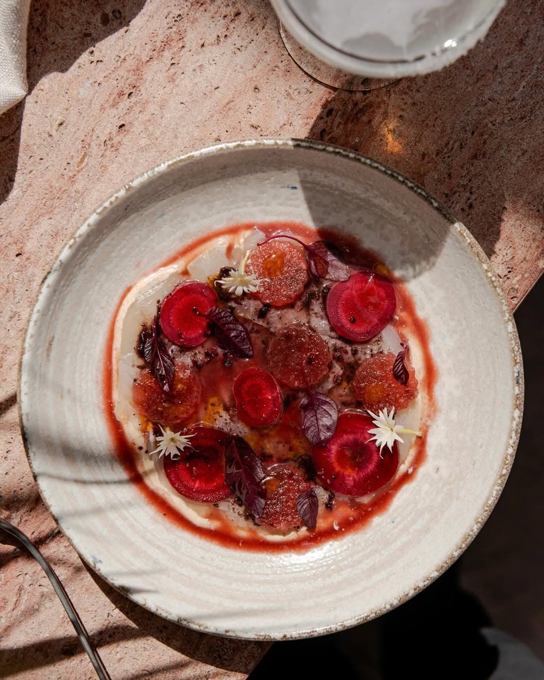 A plate of crudo in dappled light from rooftop bar lottie in redfern.