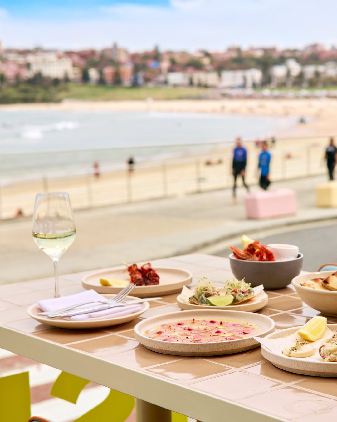 A table of seafood dishes overlooking Bondi Beach at North Bondi Fish.