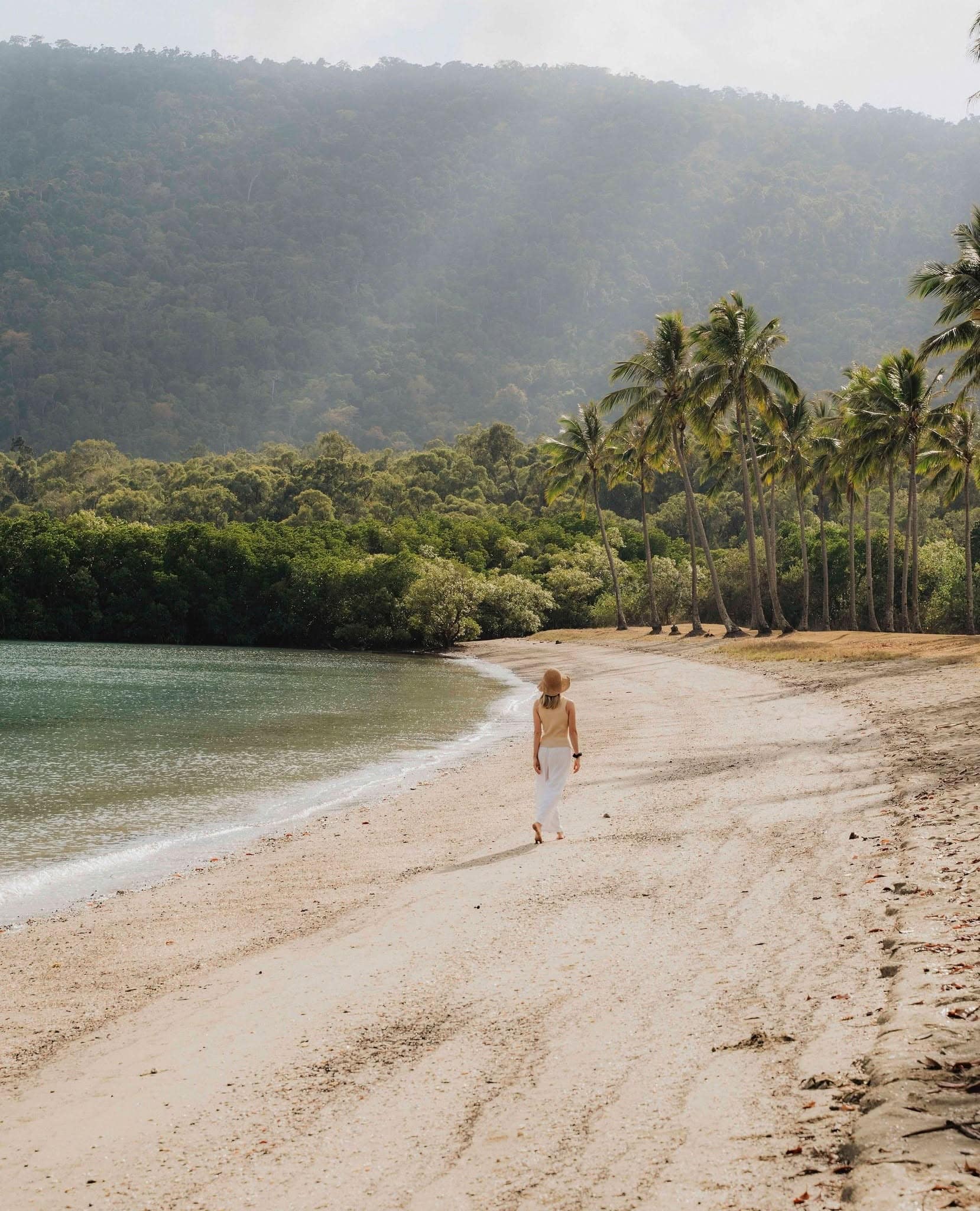 Woman walking along tropical beach near Yangaro Resort in Airlie Beach, Queensland.