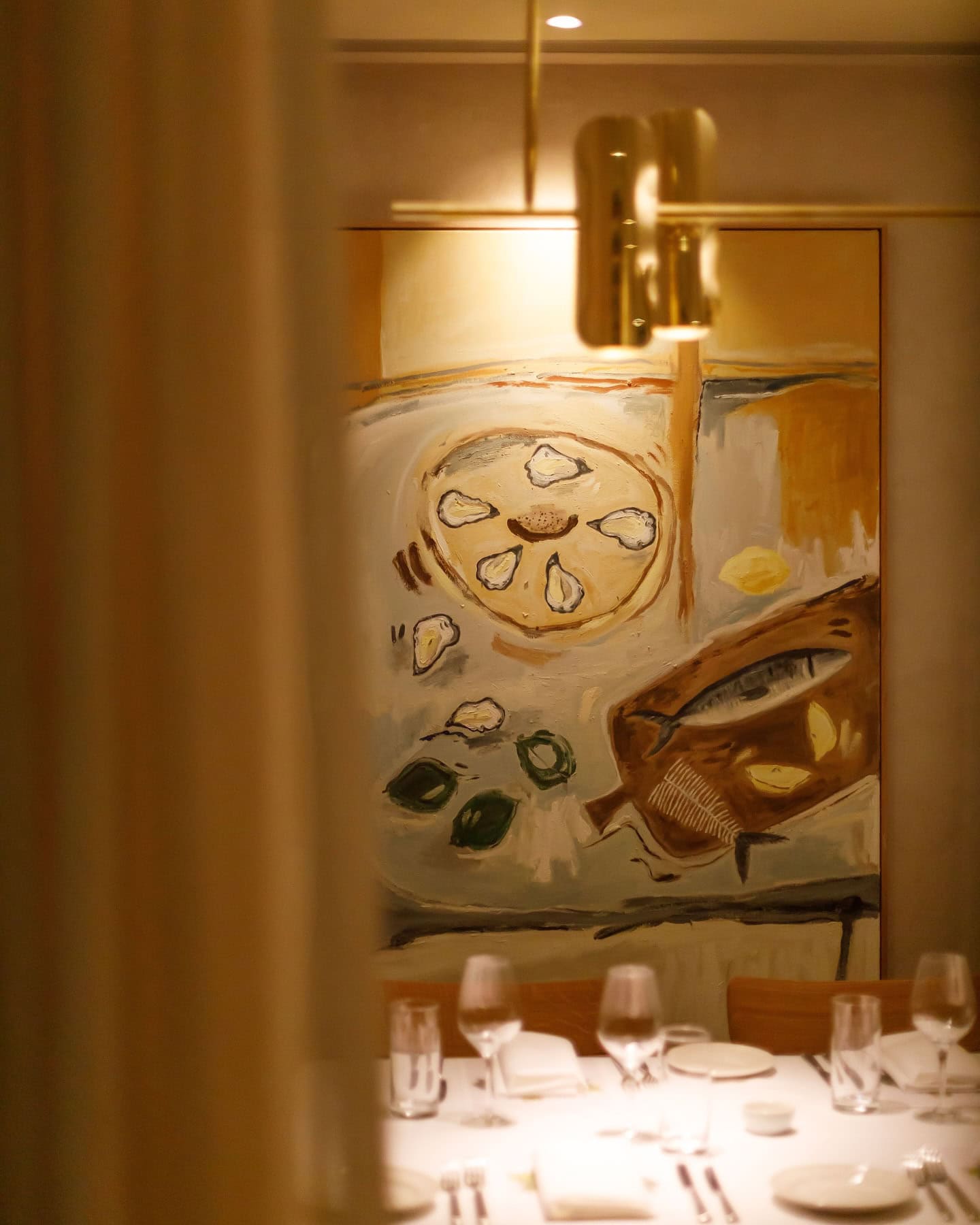 A close up of a seating area at Margaret in double bay, featuring a lit up artwork of oysters in the background.
