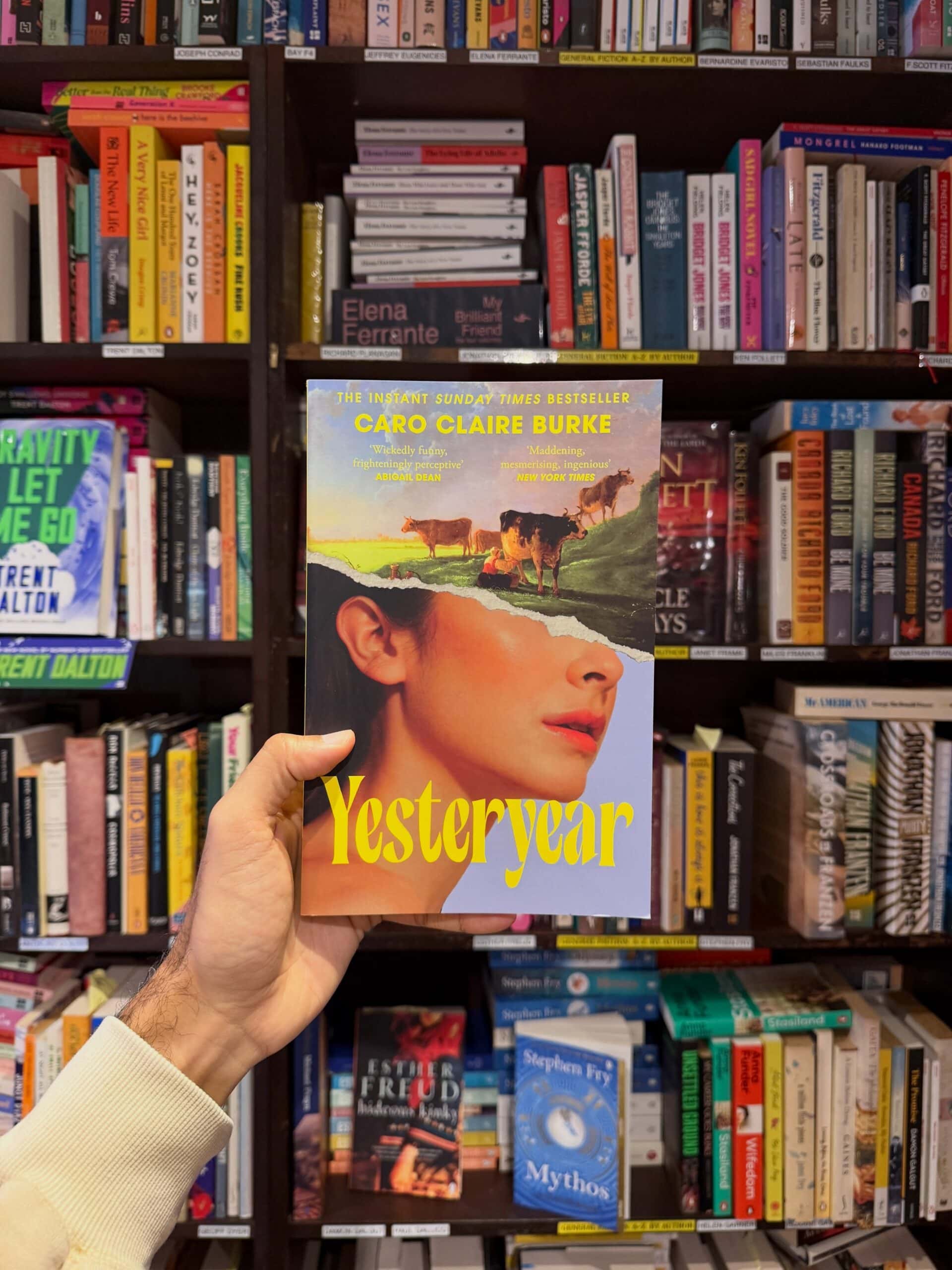Yesteryear book held up in front of shelves at Gertrude and Alice Bondi Beach Sydney