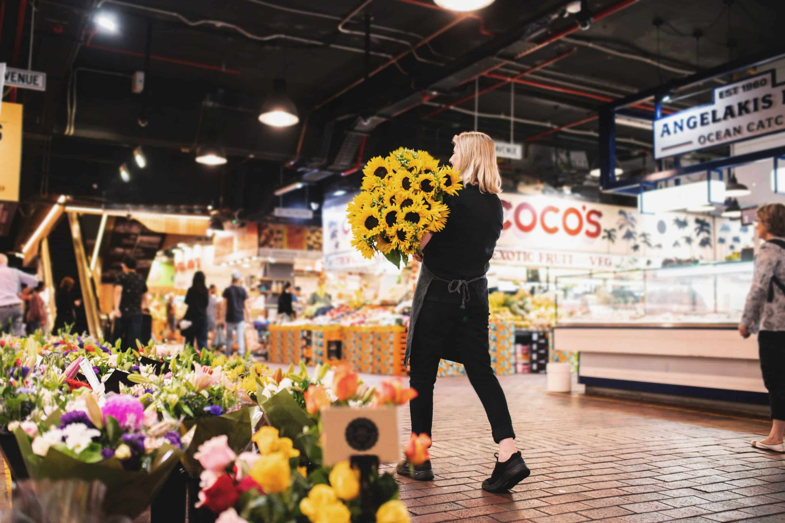 Vendor carrying flowers at Adelaide Central Market.