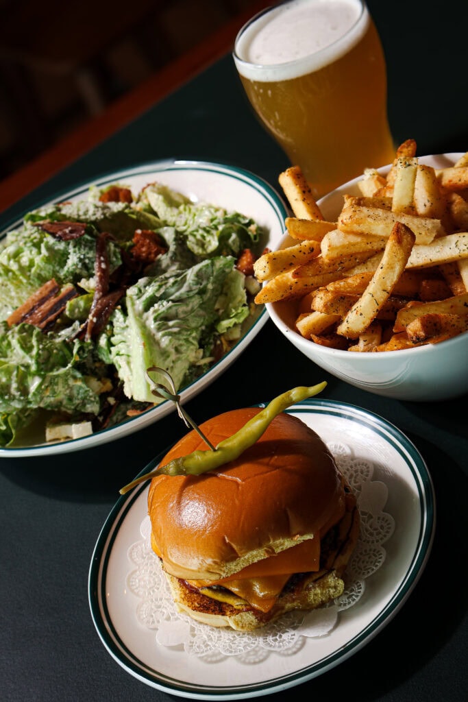 the mona social cheeseburger with a side of salted fries caesar salad and a beer
