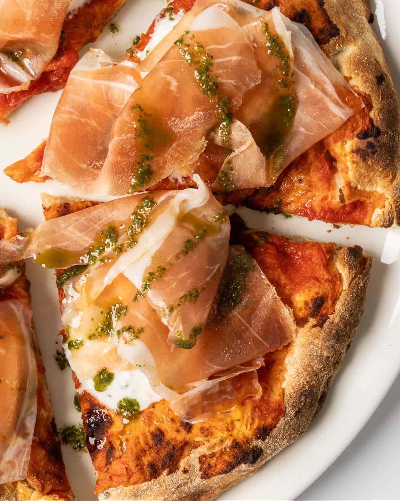 Prosciutto and basil pizza with melted cheese and crispy crust.
