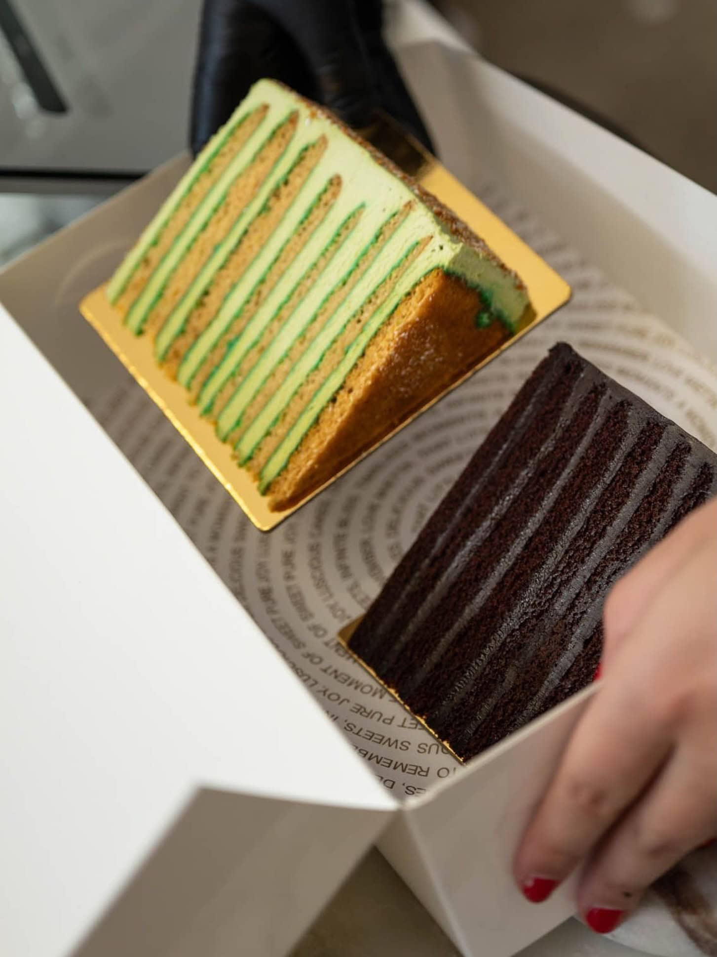 Slices of layered green tea and chocolate cake boxed at Mietta by Rosemary, Malvern.