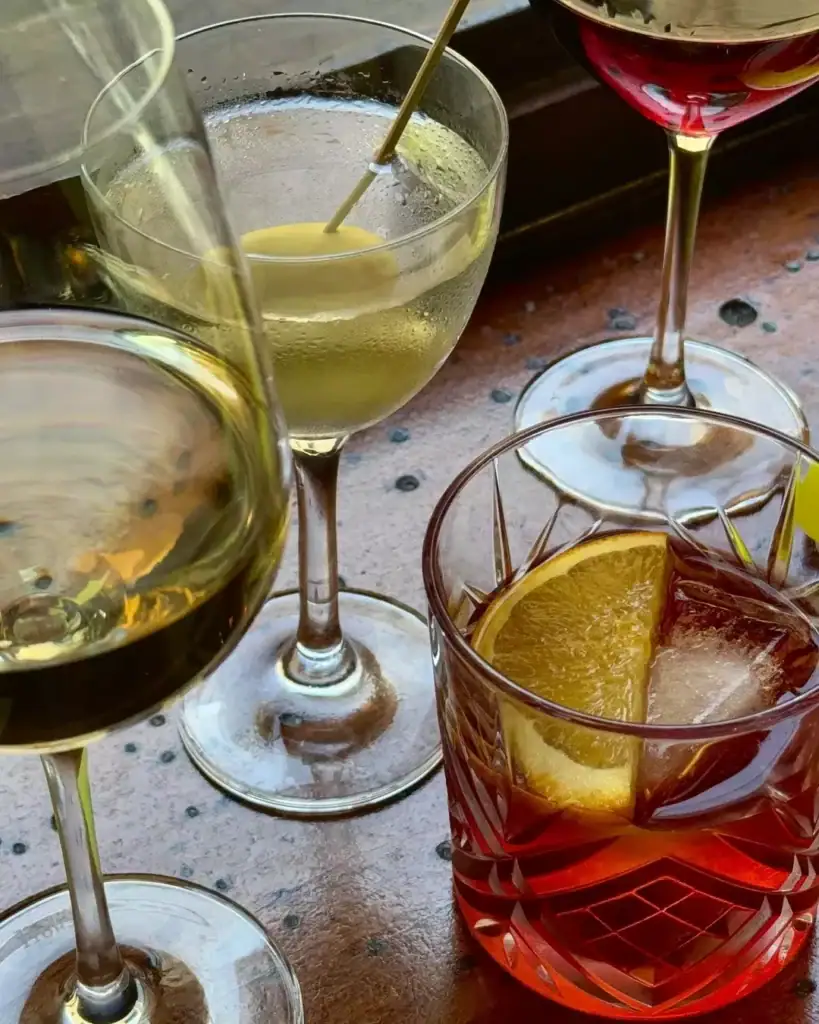 multiple different drinks on a table at love, tilly devine including a negroni, martini and wine 