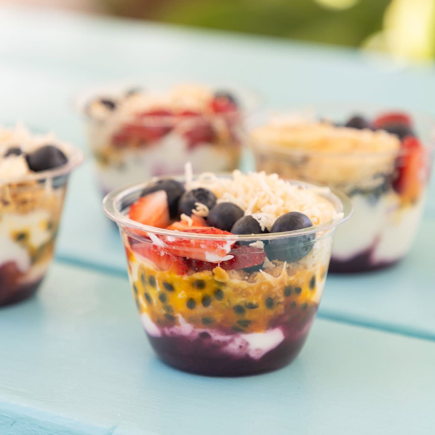 A group of colourful acai bowls on an aqua table at cook at kurnell.