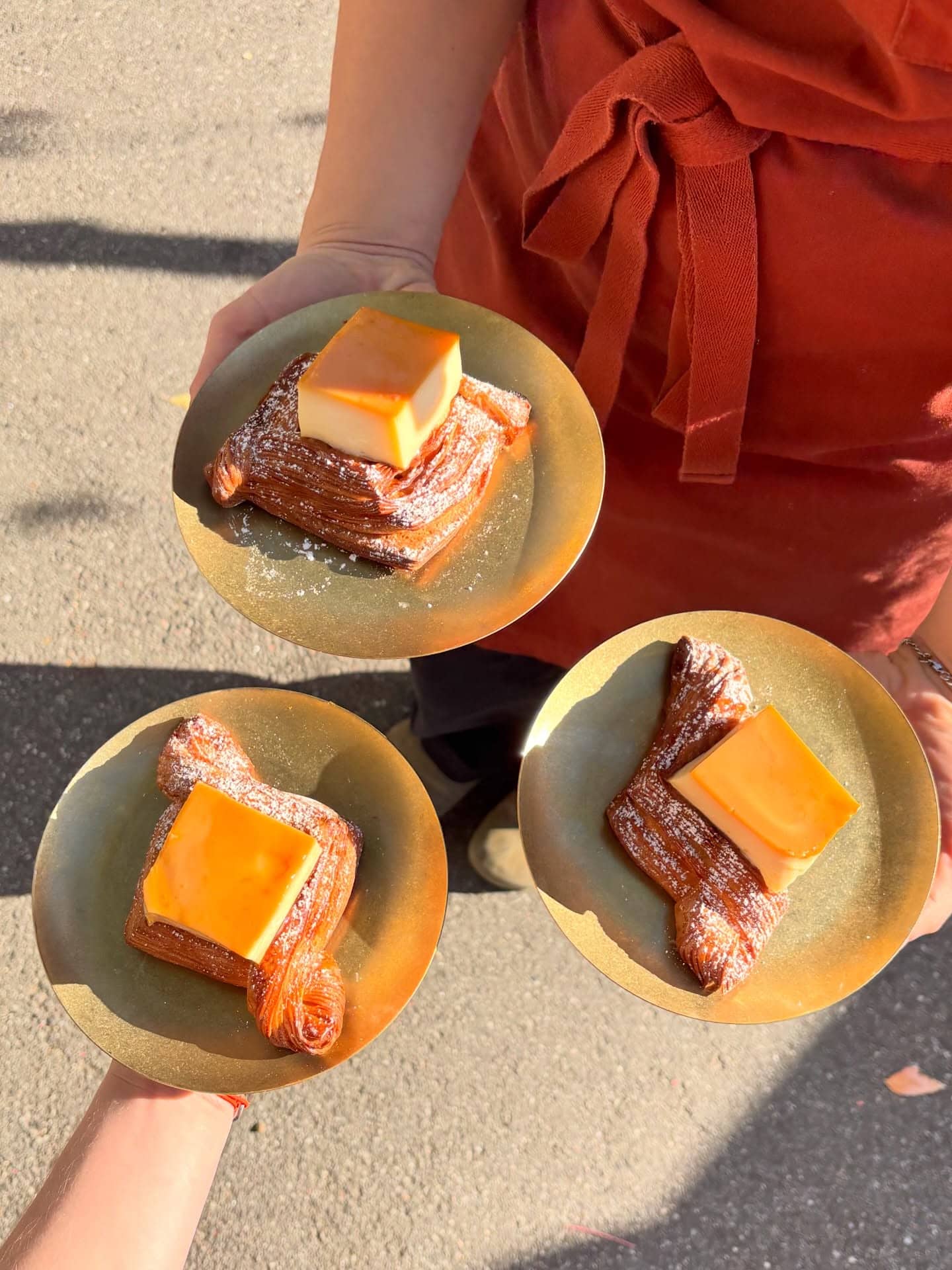 Three laminated pastries served on gold plates at Amann Patisserie in Melbourne.
