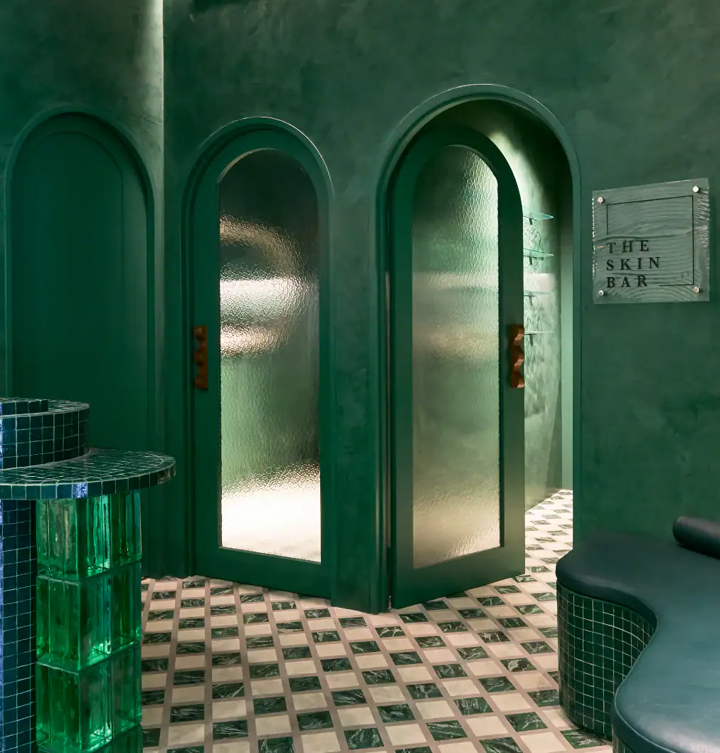 Arched frosted glass treatment room doors with green marble checkered floor and glass block pedestals at The Skin Bar Manly Sydney
