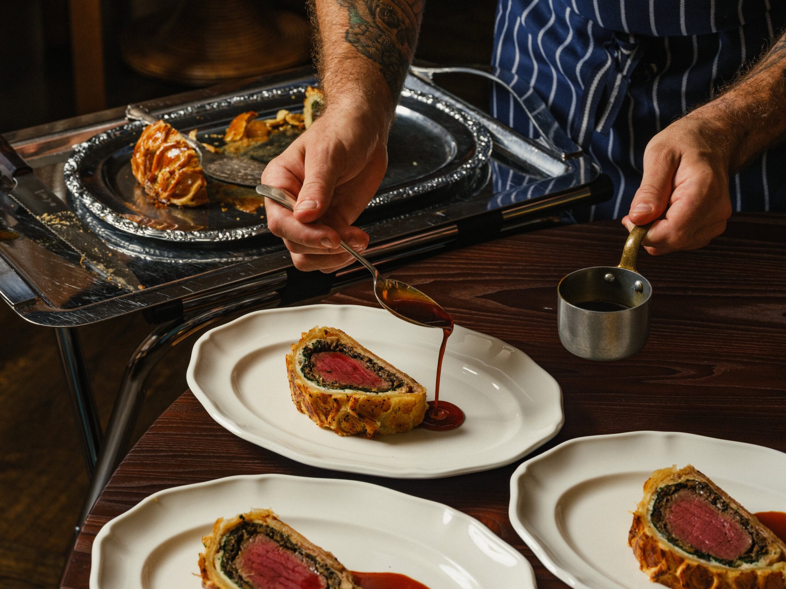 A waiter pouring gravy over slices of beef wellington at The James in Sydney.