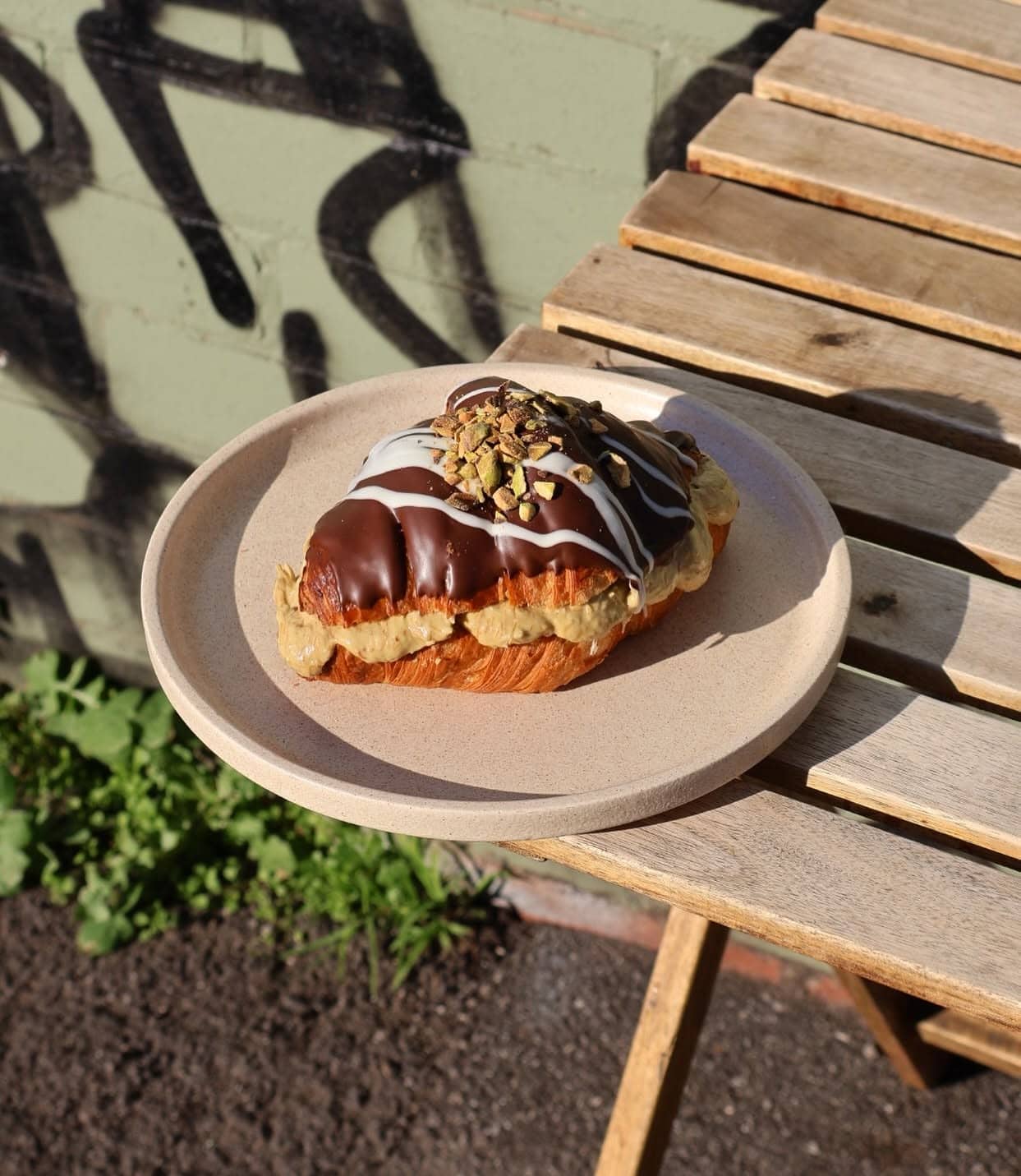 Chocolate-coated croissant filled with pistachio cream and topped with chopped pistachios at Calle Bakery Melbourne.
