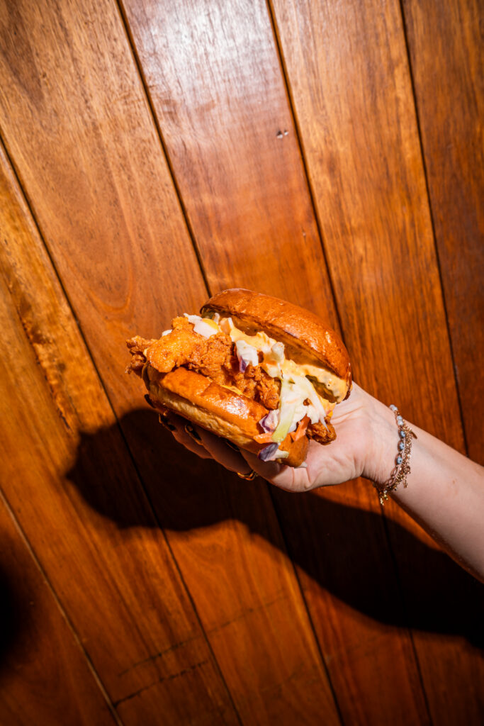 Crispy charcoal chicken burger with coleslaw and house-made sauce held up at Char'd Chicken Eastern Creek Sydney