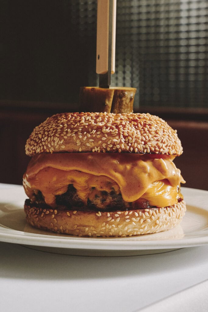 Wood-fired beef cheeseburger with melted American cheese caramelised onions and dijonnaise on sesame bun at Clam Bar Sydney CBD