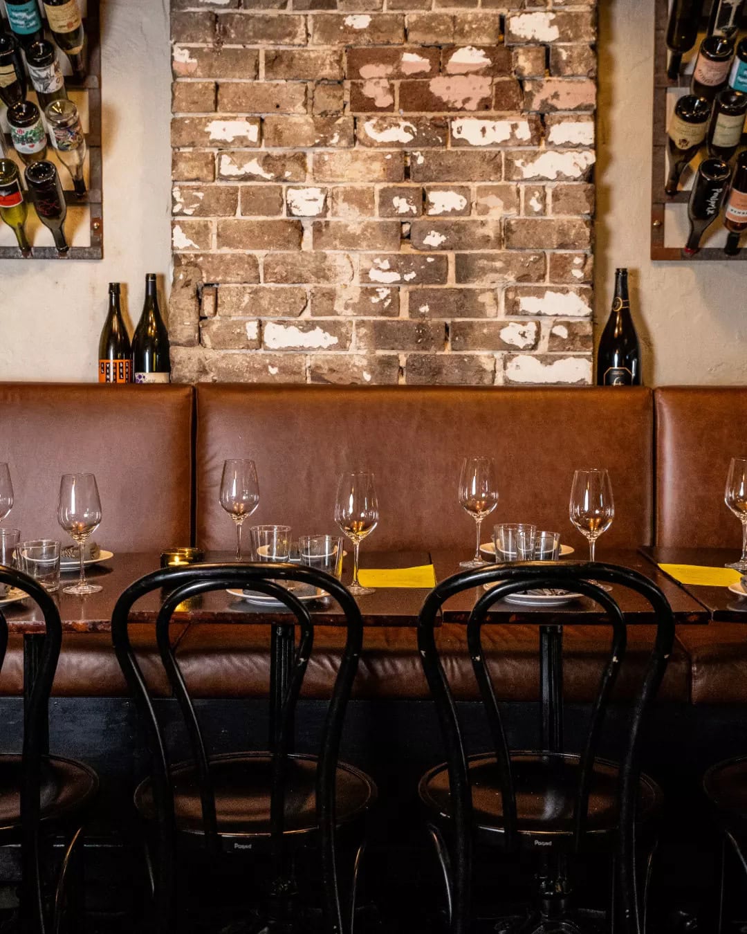The warm dining room of Love, Tilly Devine, complete with exposed brick walls and brown leather banquette seating.