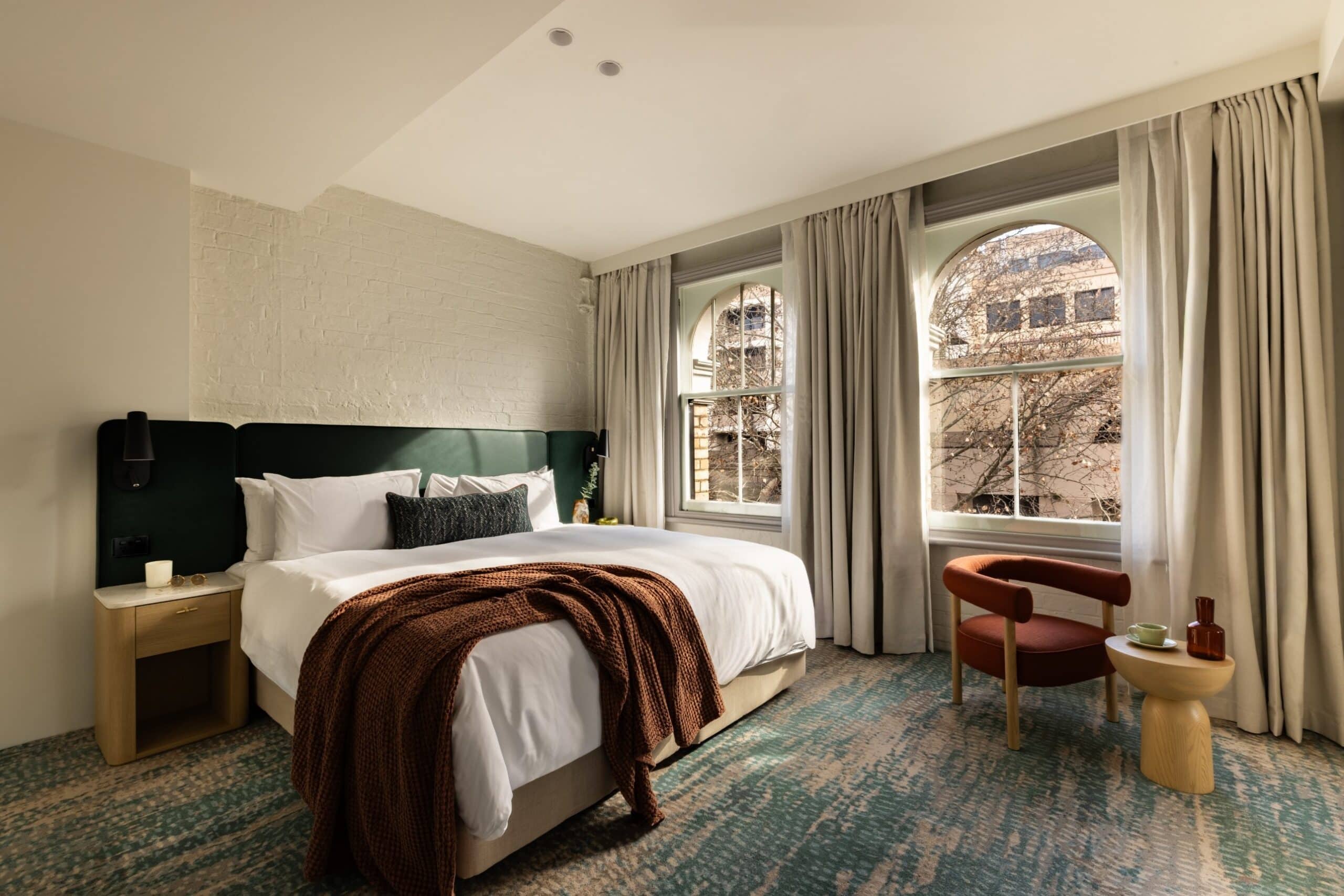 Hotel room with green headboard and arched windows at Harbour Rocks Hotel The Rocks Sydney