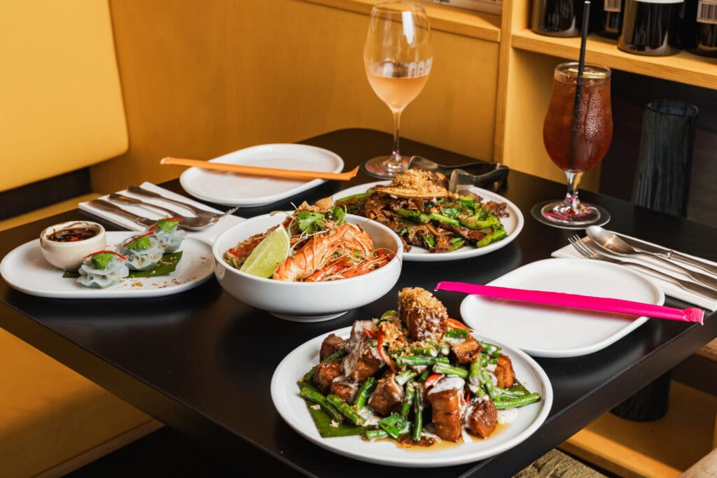 A table laid with multiple dishes at Naga Thai in Brisbane.