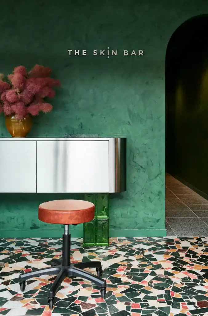 Reception desk with The Skin Bar signage emerald plaster walls and colourful terrazzo floor at The Skin Bar Manly Sydney