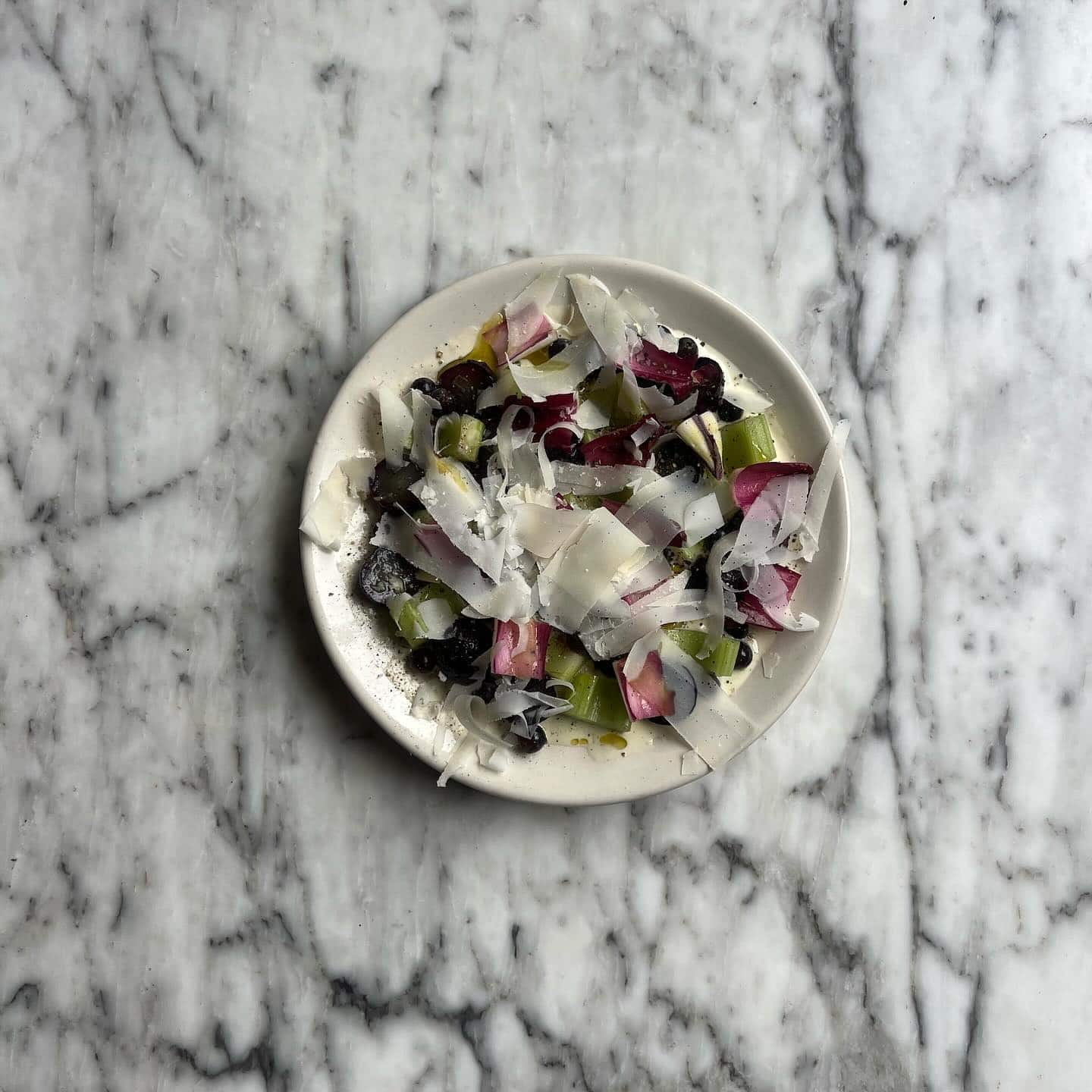 A colourful bowl of salad from famed Sydney restaurant Ester, sitting atop a white marble table.