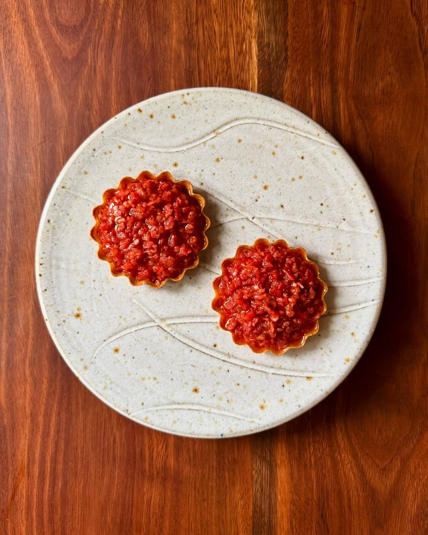 two delicate tomato tarts atop a white plate and wooden table at sixpenny in sydney.