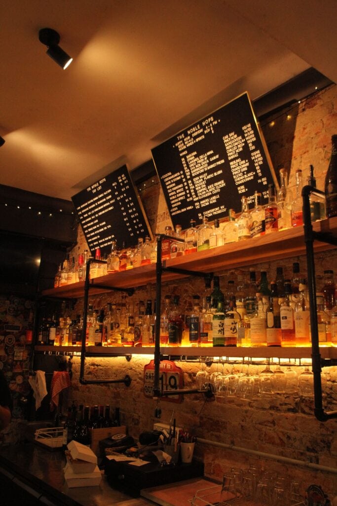 The lowlit interiors of The Noble Hops in Redfern, featuring the famous rotating letter boards and shelves of spirits.
