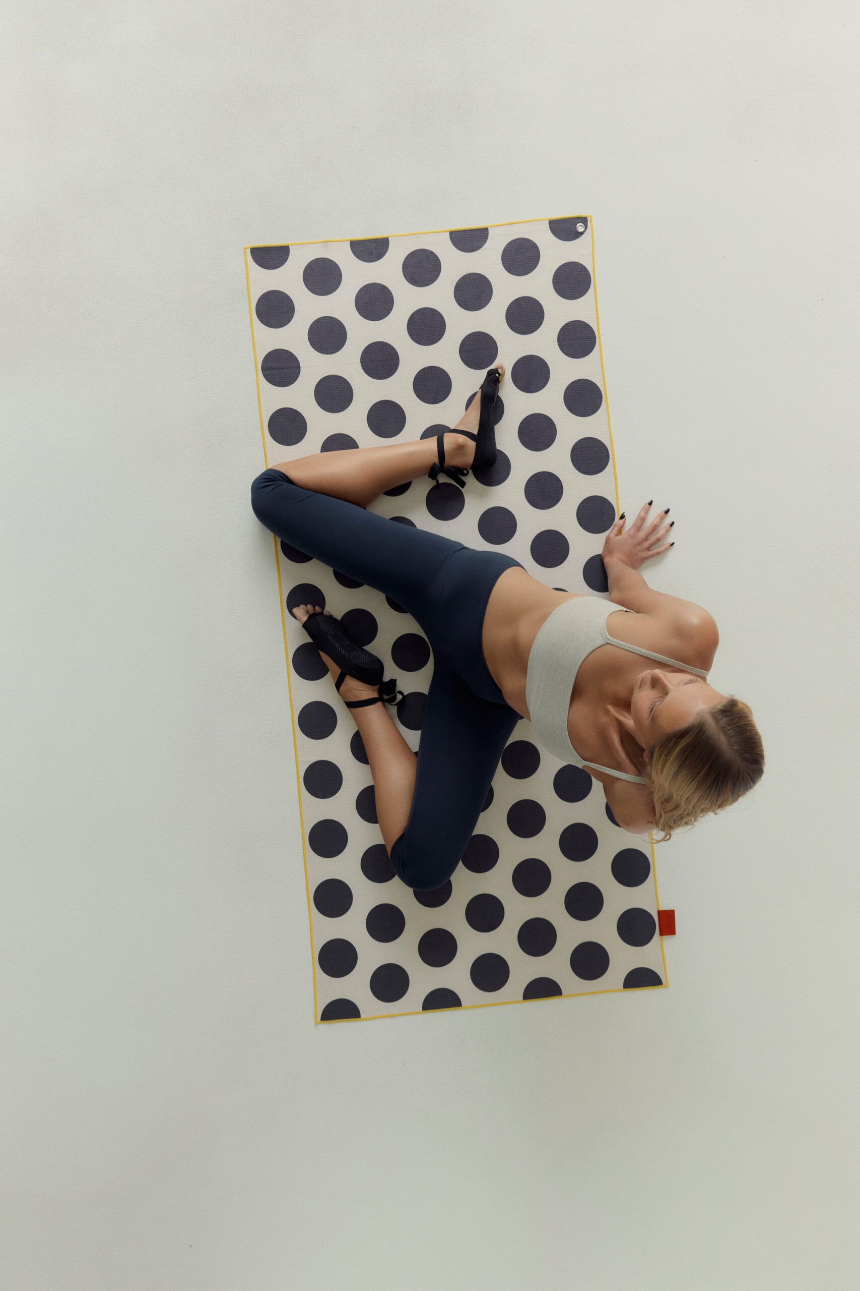 Model doing pilates on Clammy polka dot waffle-weave yoga towel mat with carabiner clip