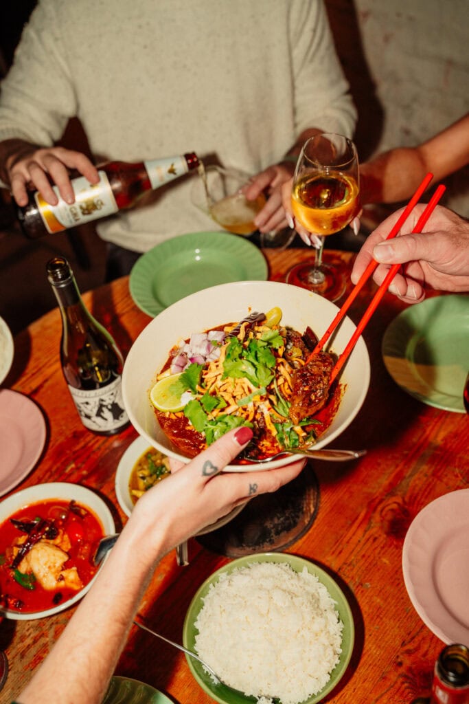 someone passing a bowl of Thai curry over a table at Long Chim's Curry Night in Perth