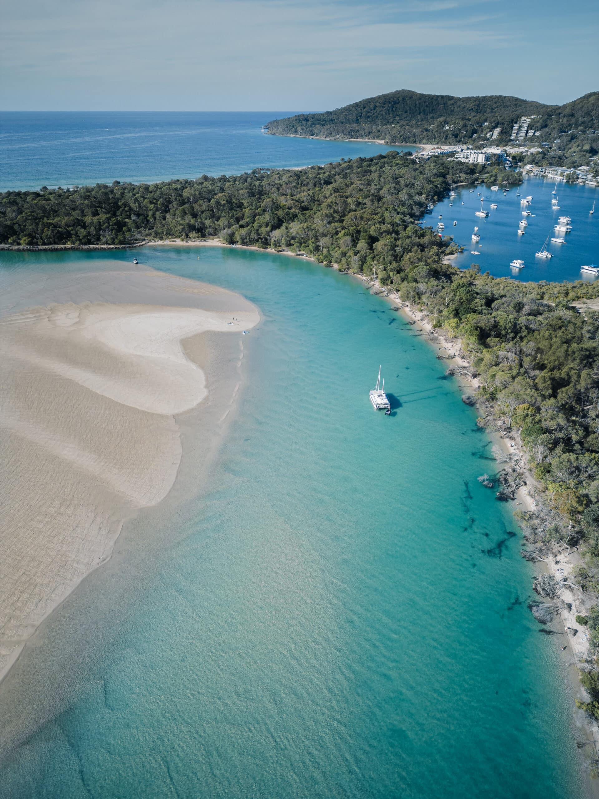 Noosa River aerial view, blue water, white boat bobbing in the turquoise water