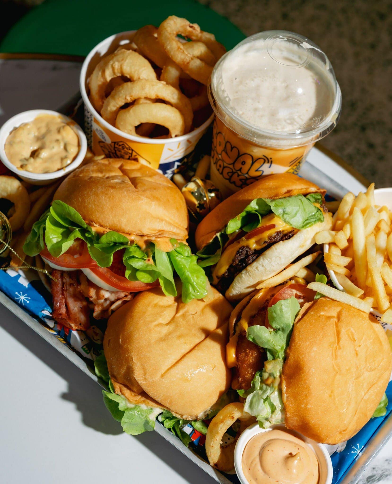 Selection of burgers, onion rings, chips and sauces and a milkshake at Royal Stacks, a Melbourne burger restaurant.