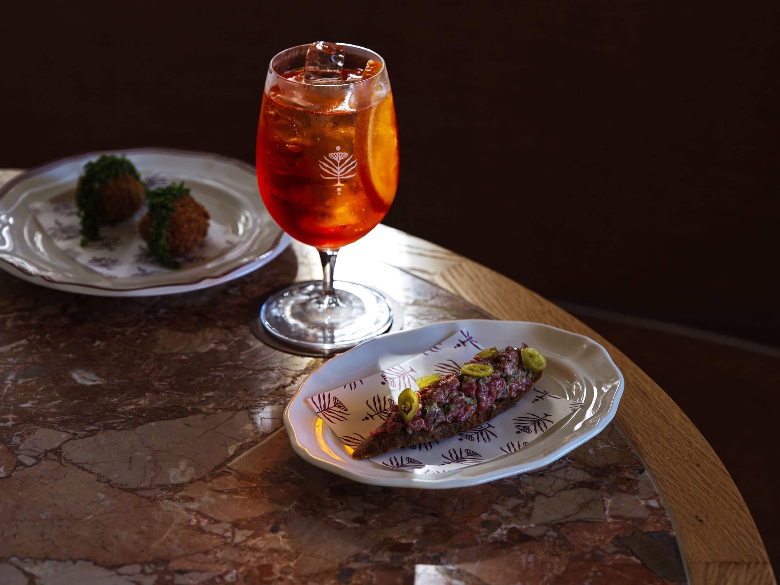 Aperitivo spritz with beef tartare on toast and arancini on marble table at Meadow Cronulla Sydney