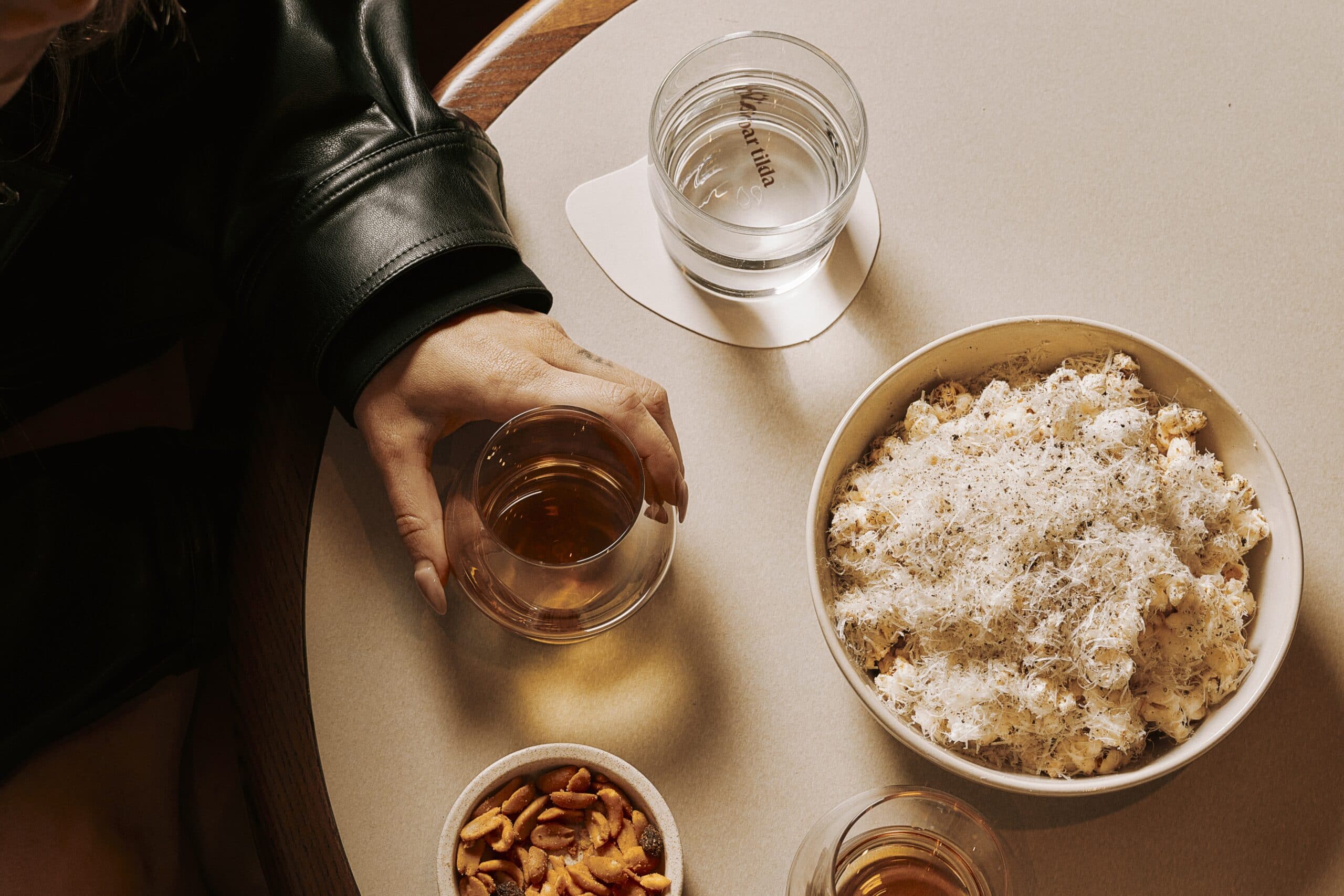 Bar Tilda cacio e pepe popcorn with pecorino and black pepper in bowl on table with whisky and water Sofitel Sydney Wentworth CBD