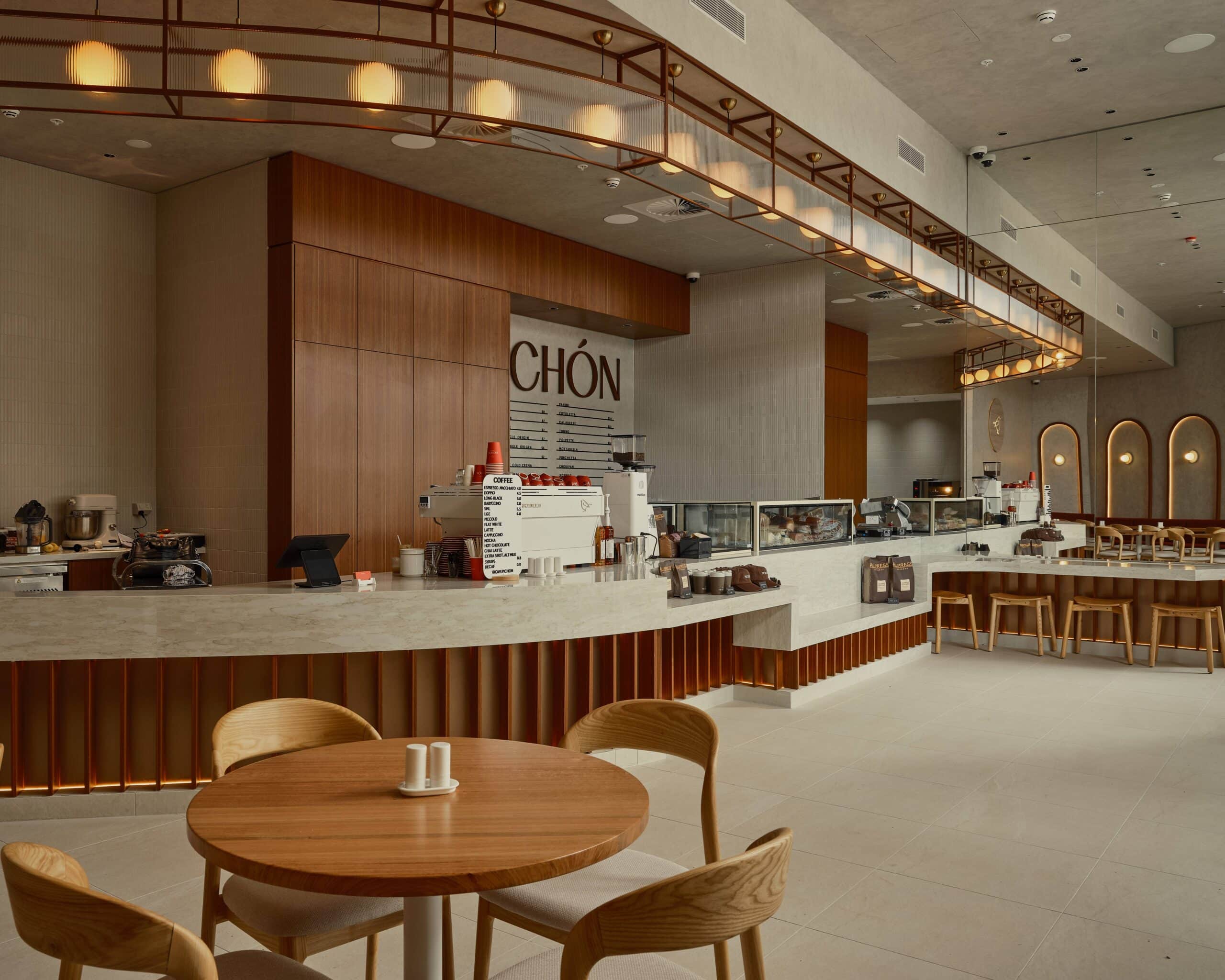 Curved marble cafe counter with timber joinery pendant lights and deli display Pichon Norwest Sydney