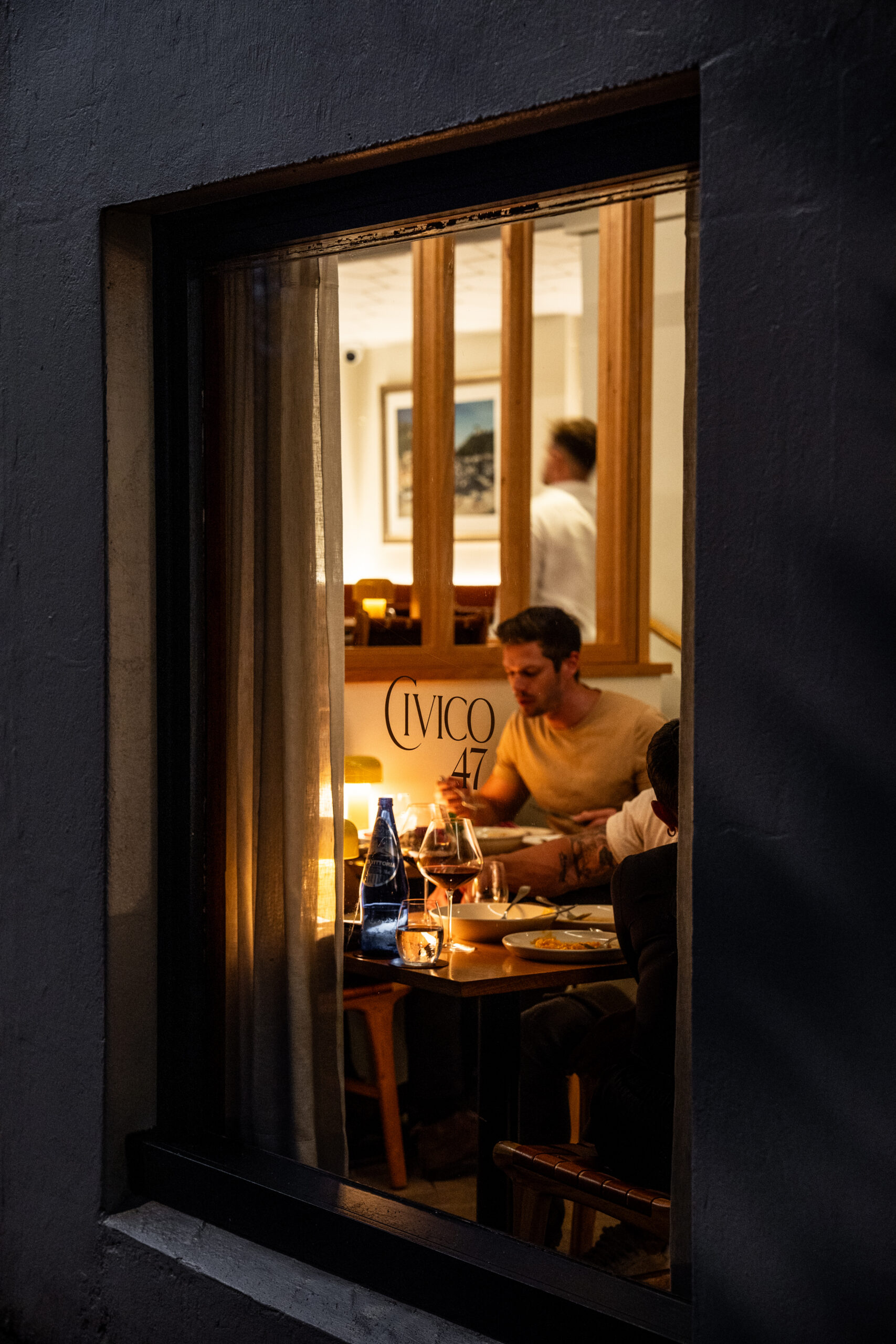 Candlelit dining room with diners at table viewed through street window at Civico 47 Paddington Sydney