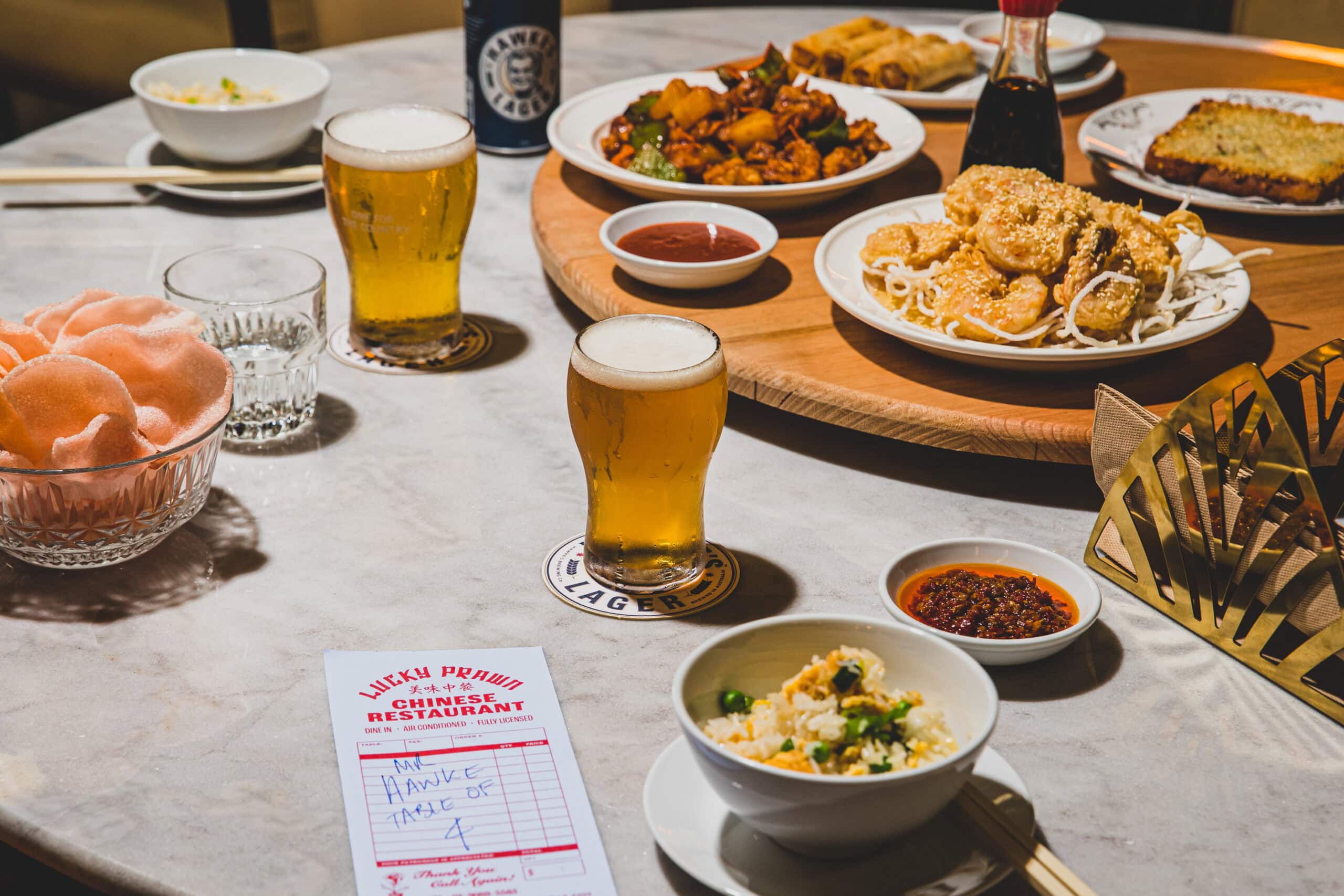 Chinese share plates with salt and pepper prawns fried rice prawn crackers and Hawke lager on lazy susan at The Bob Hawke Beer and Leisure Centre Newtown Sydney
